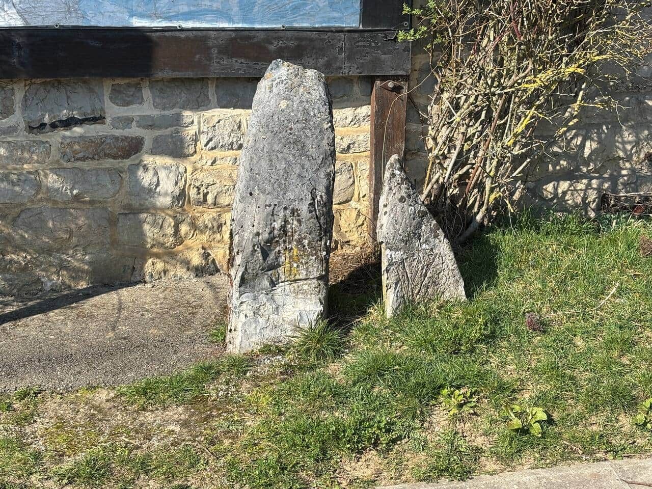 Un muro de piedra con una puerta de madera y un pilar de piedra al frente.