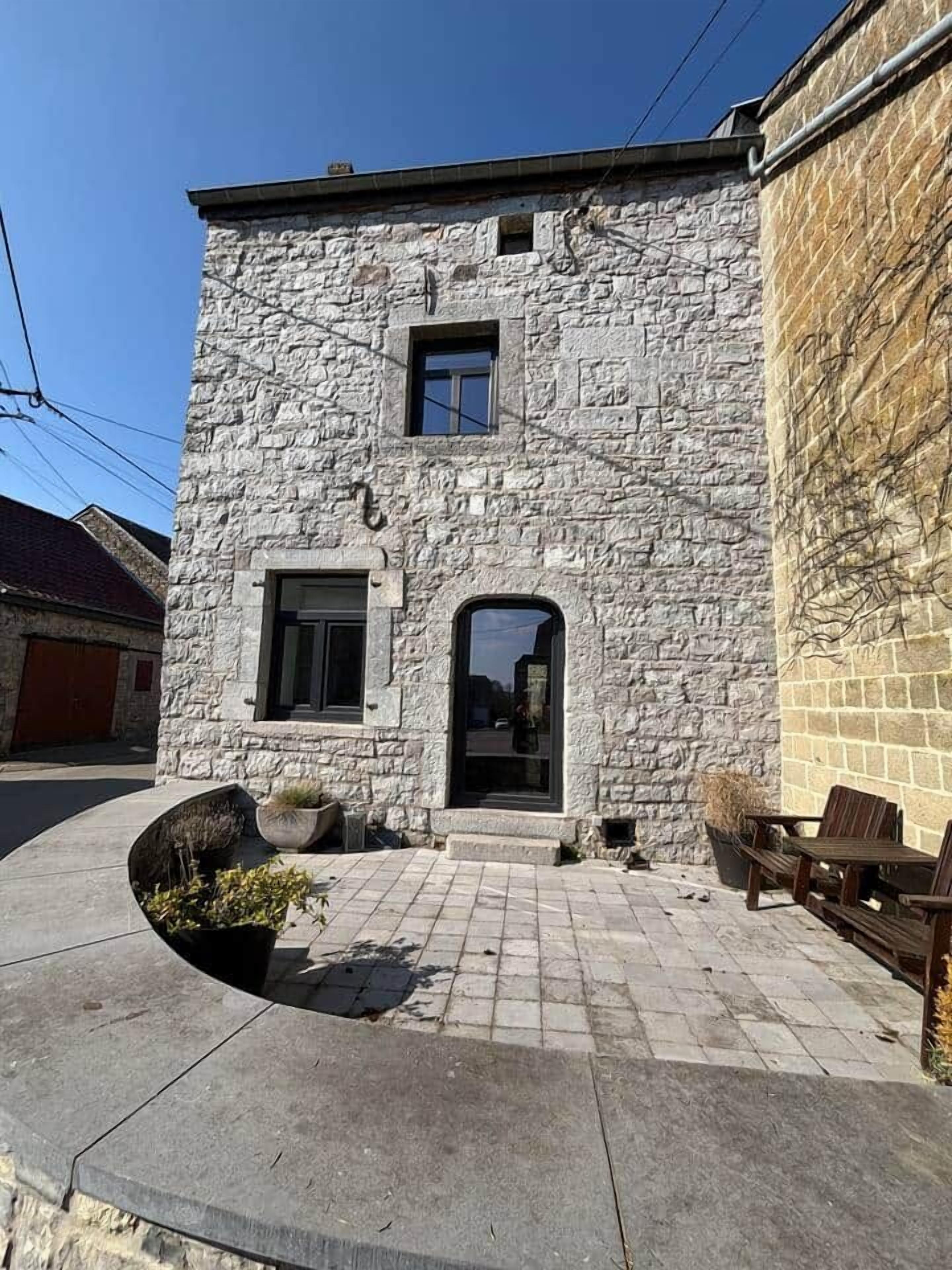 Il s’agit d’un bâtiment en pierre doté d’une petite entrée, d’une fenêtre et d’une porte. On y trouve une zone pavée avec un jardinier et du mobilier d’extérieur.