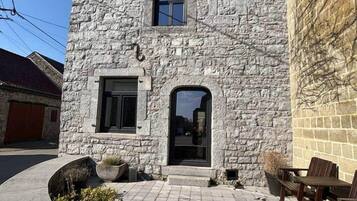 Il s’agit d’un bâtiment en pierre doté d’une petite entrée, d’une fenêtre et d’une porte. On y trouve une zone pavée avec un jardinier et du mobilier d’extérieur.