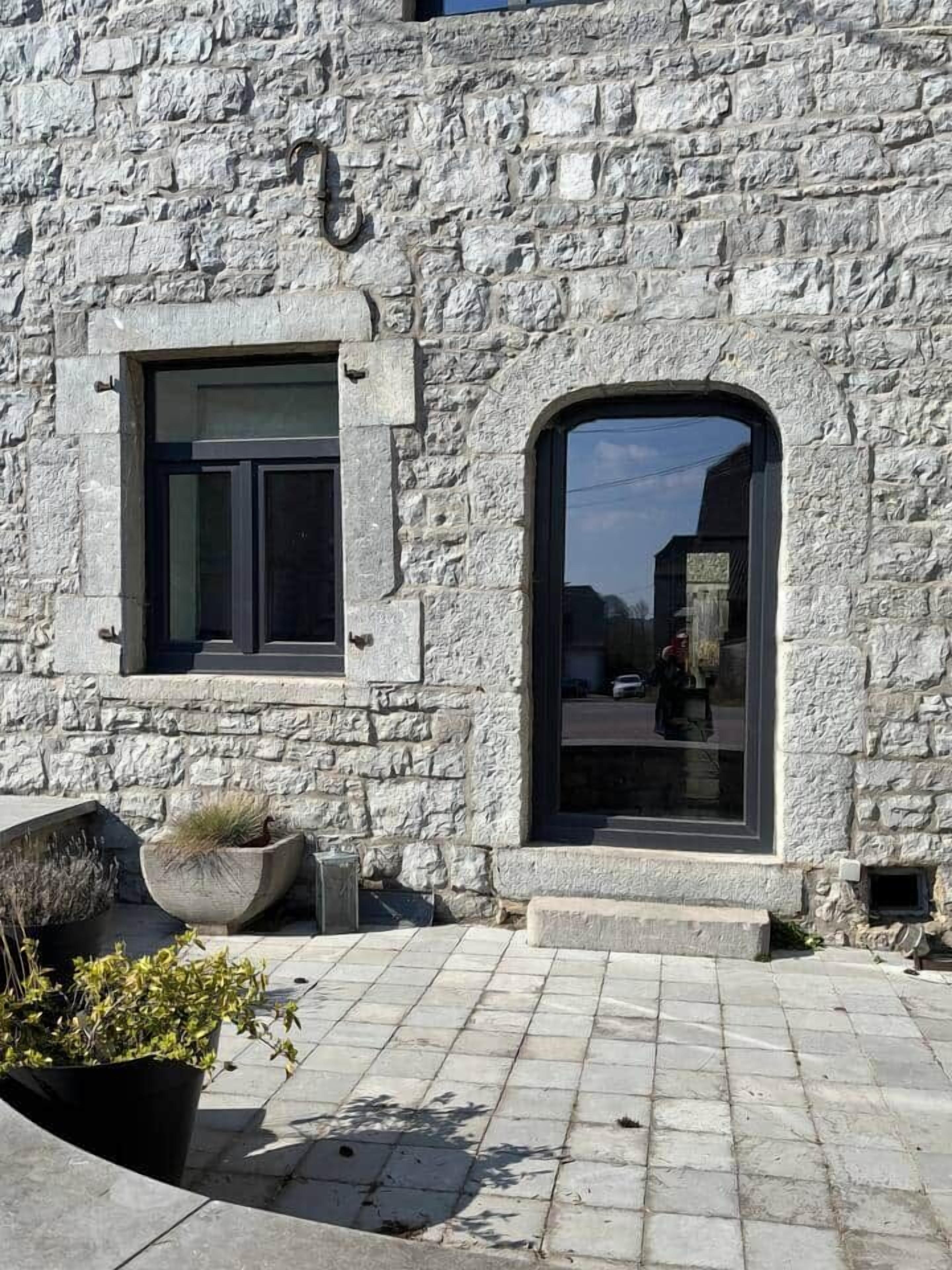 A stone building with a window and an arched doorway.