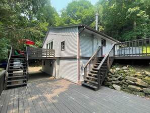 A two-story house with a deck, a staircase, and a small shed.
