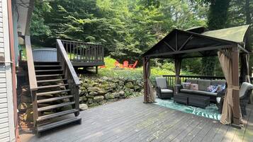 A wooden deck with a gazebo, outdoor seating, and a staircase leading to a deck area.