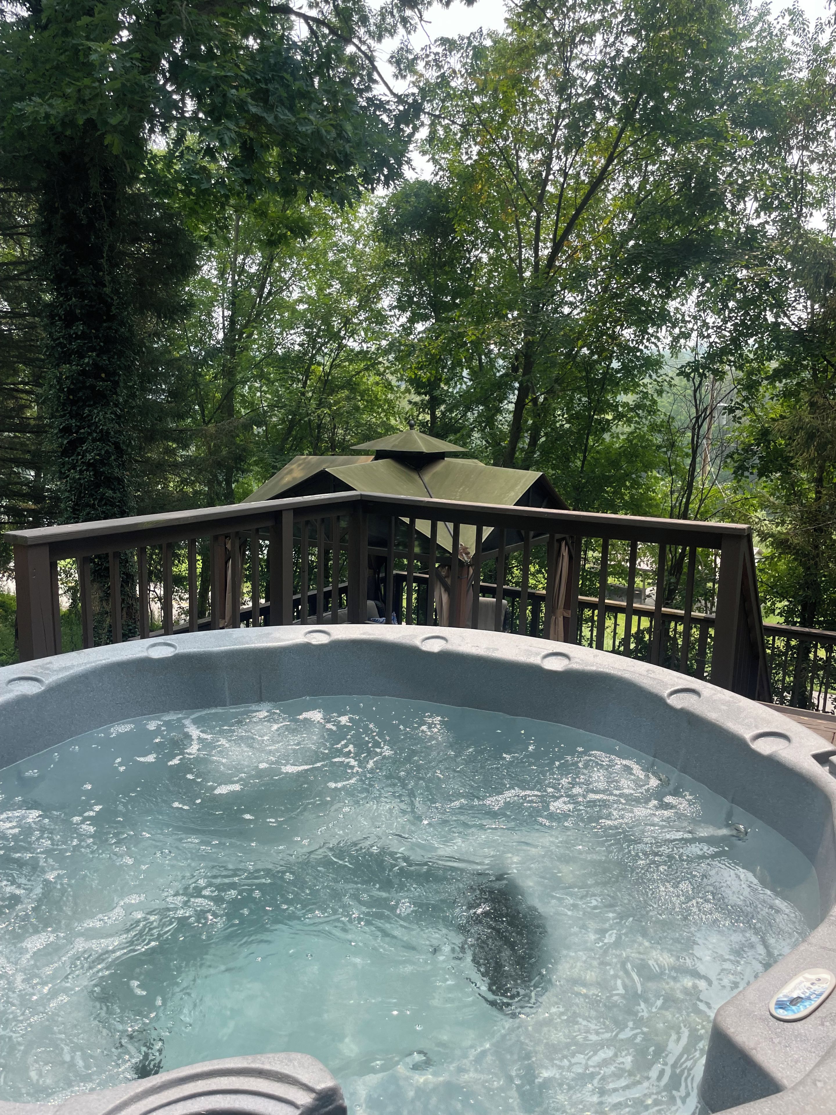 Un jacuzzi rodeado por una terraza de madera y árboles.