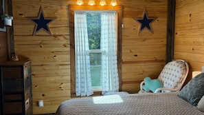 A wooden-paneled room with a bed, a dresser, and two star decorations on the wall. - Let the Kids & Dogs play While you relax! 2Br/1B, Close to i20 & town (Kilgore)