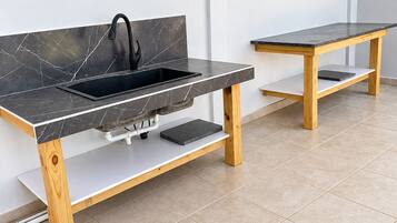 Eine moderne Küche mit integriertem Spülbecken, Holztisch und Fliesenboden.