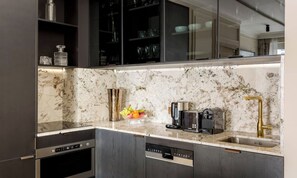 A modern kitchen with a built-in dishwasher, a coffee maker, and a sink with a gold faucet.