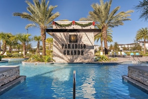 A pool area with a sign reading 'PARADISO GRANDE' and palm trees. - Luxury 15br Suites, Pool and Themed Bedrooms (Orlando)