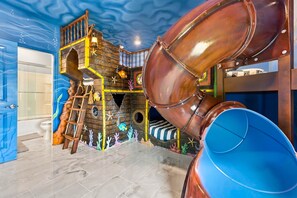 A play area with a slide, climbing structures, and a ship-themed design. - Luxury 15br Suites, Pool and Themed Bedrooms (Orlando)