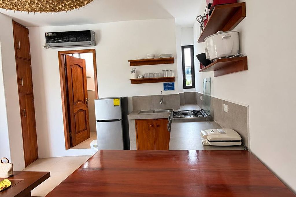A compact kitchen with wooden cabinets, a refrigerator, a stove, and a microwave.