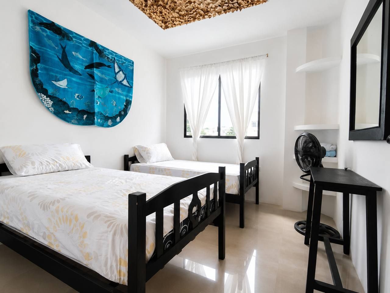 Un dormitorio con dos camas, un escritorio y un ventilador.