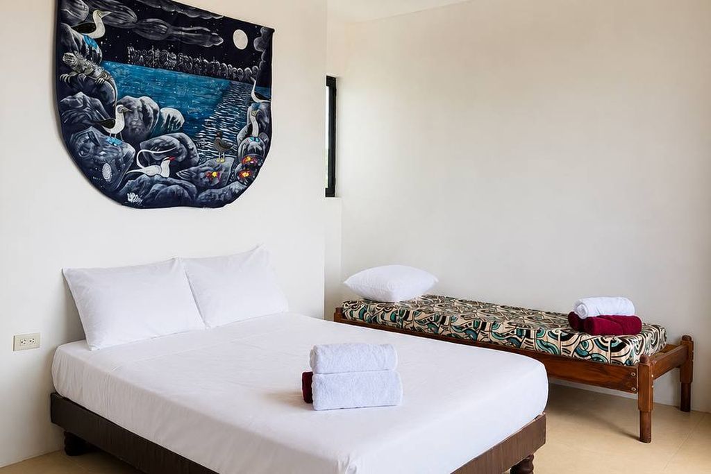 Una habitación de hotel con una cama grande, otra más pequeña y un tapiz en la pared.