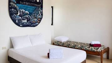 Una habitación de hotel con una cama grande, otra más pequeña y un tapiz en la pared.