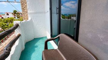 Un balcon donnant sur la mer, une chaise et un mur blanc.