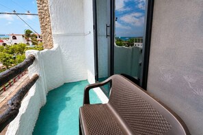 Un balcon donnant sur la mer, une chaise et un mur blanc.