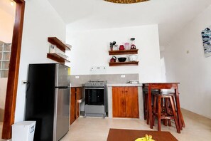 Une cuisine de taille réduite, équipée d’un réfrigérateur, d’une cuisinière et de meubles de rangement en bois.