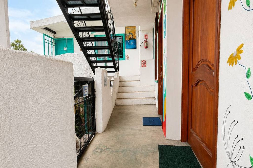 Un pasillo estrecho con una escalera, una puerta de madera y un papel tapiz con estampado floral.
