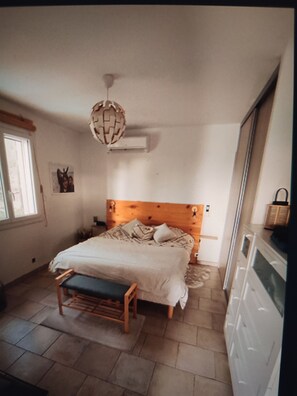 A bedroom with a wooden bed, a bench, a hanging light fixture, and a window. - A quiet house near Avignon and Saint-Rémy-de-Provence, with a view of the Alpilles (Châteaurenard)