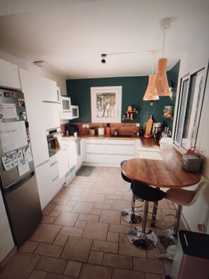 A kitchen with a wooden dining table, a refrigerator, and a microwave. - A quiet house near Avignon and Saint-Rémy-de-Provence, with a view of the Alpilles (Châteaurenard)