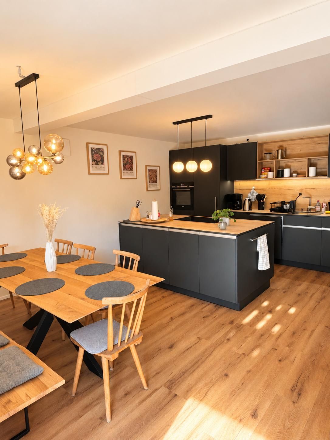 A modern kitchen with a central island, wooden dining table, and chairs.