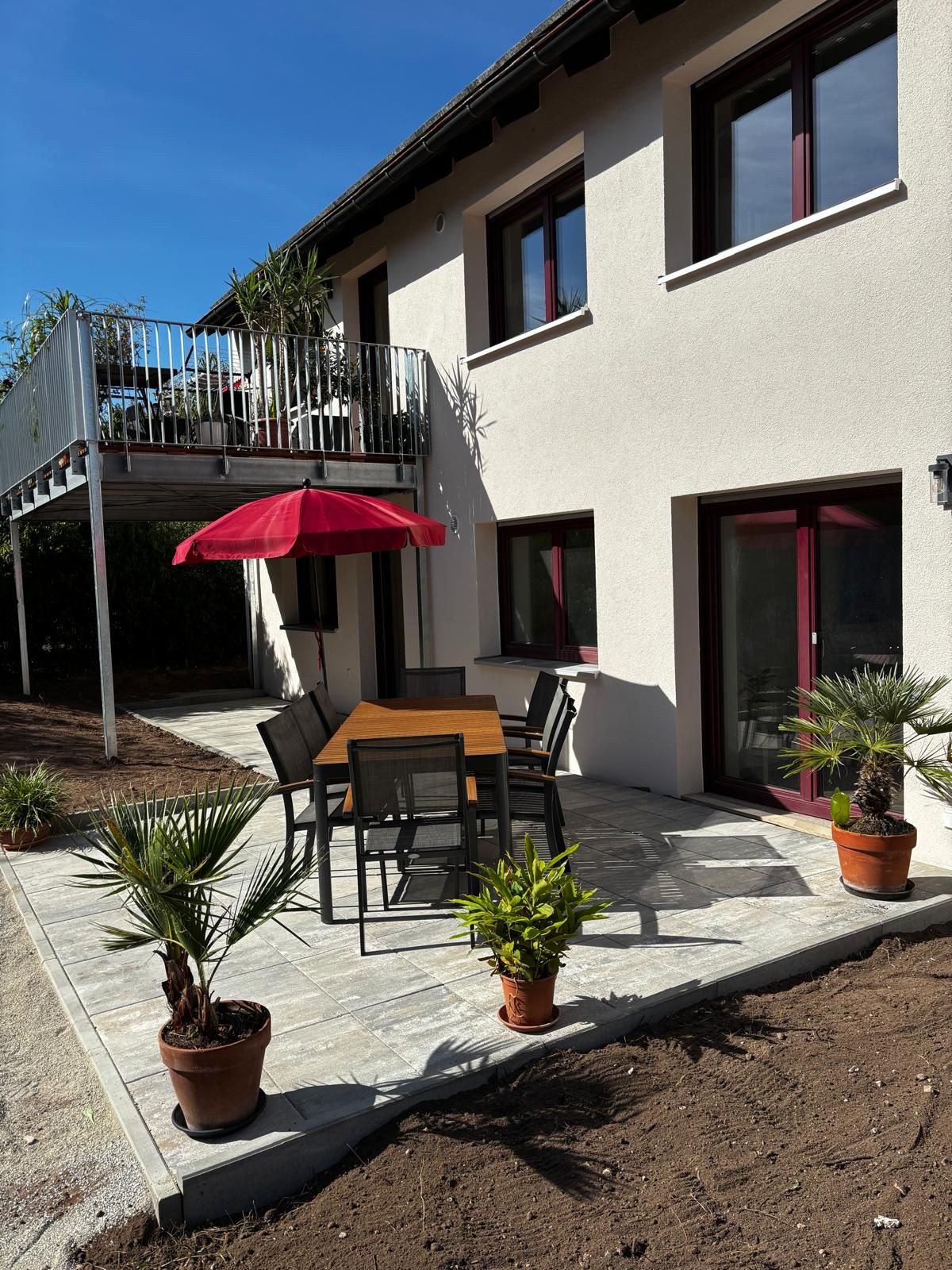 Eine Terrasse mit Tisch und Stühlen, umgeben von Topfpflanzen.