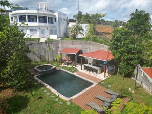 Ein Wohnhaus mit Swimmingpool, Sitzgelegenheit im Freien und einem großen Haus im Hintergrund.