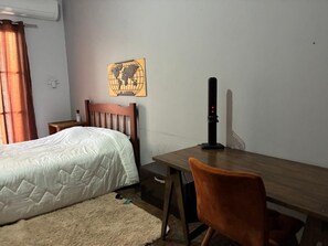A room with a bed, a desk, a chair, a globe artwork, and a wall-mounted air conditioner. - Paulista | Entire apartment of 170 m², 3 bedrooms and parking space (São Paulo)