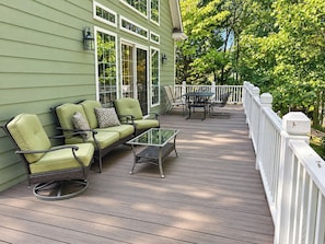Eine Holzterrasse mit Gartenmöbeln, darunter eine Sitzecke mit Sofa und Stühlen sowie einem Glastisch.
