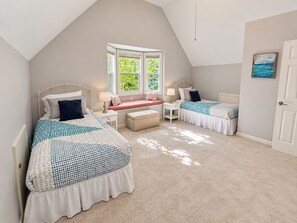 Ein Schlafzimmer mit zwei Betten, einer Bank und einem Fenster.
