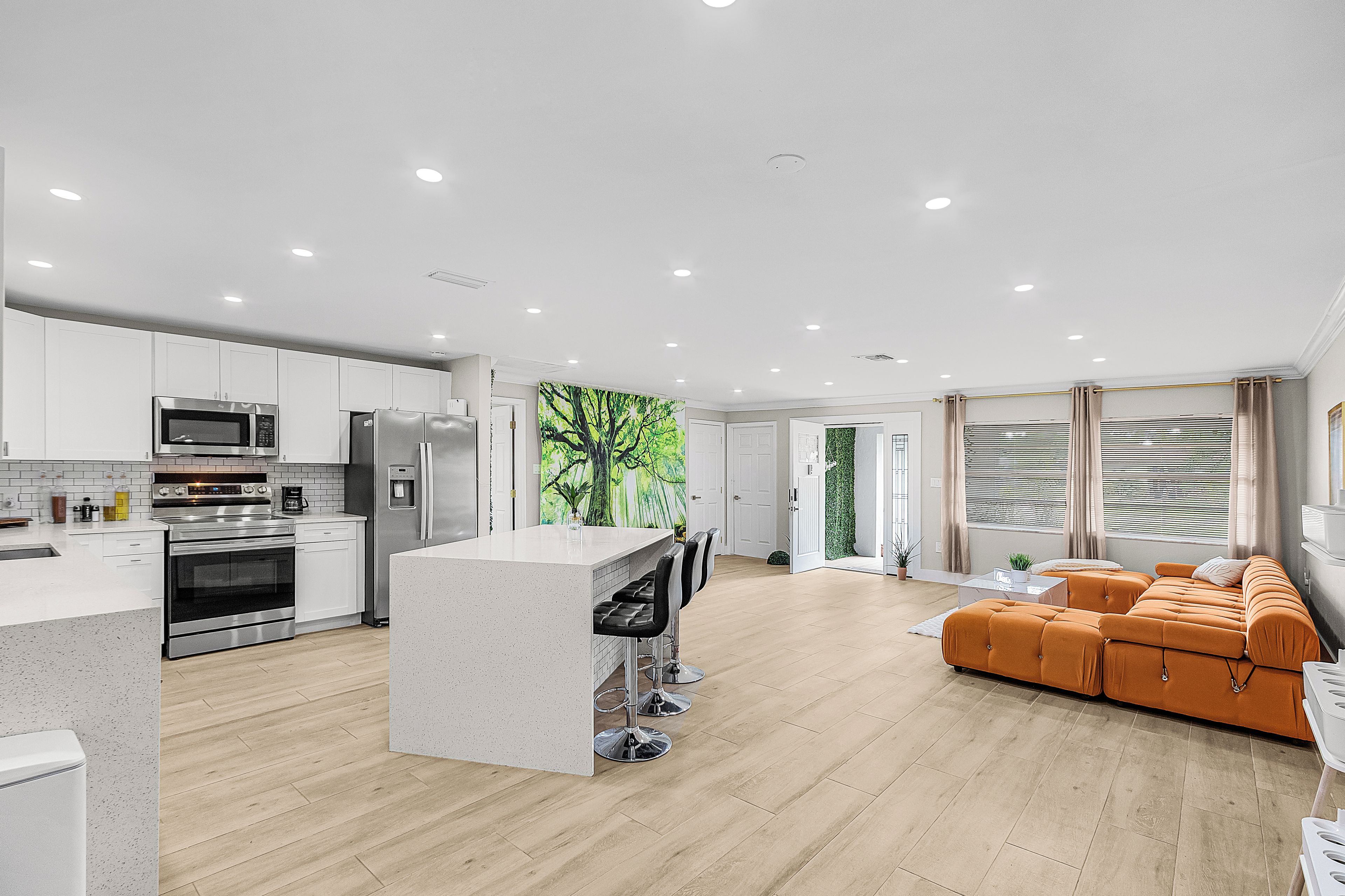 Una cocina moderna con electrodomésticos integrados, una isla central y un comedor con sofá y sillas.