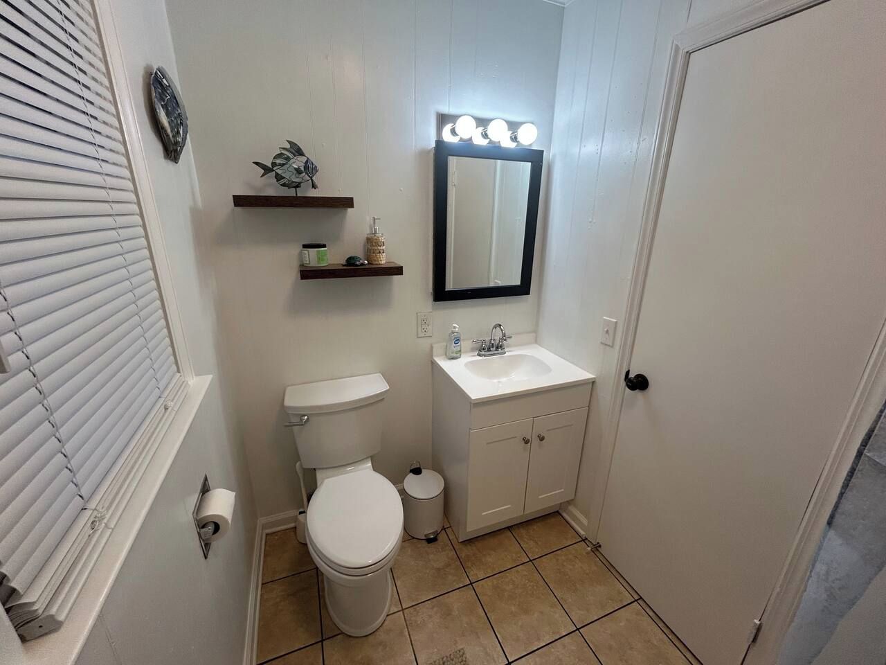 A compact bathroom with a toilet, sink, and mirror.