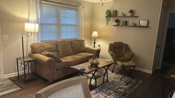A living room with a sofa, armchair, coffee table, and a ceiling fan.