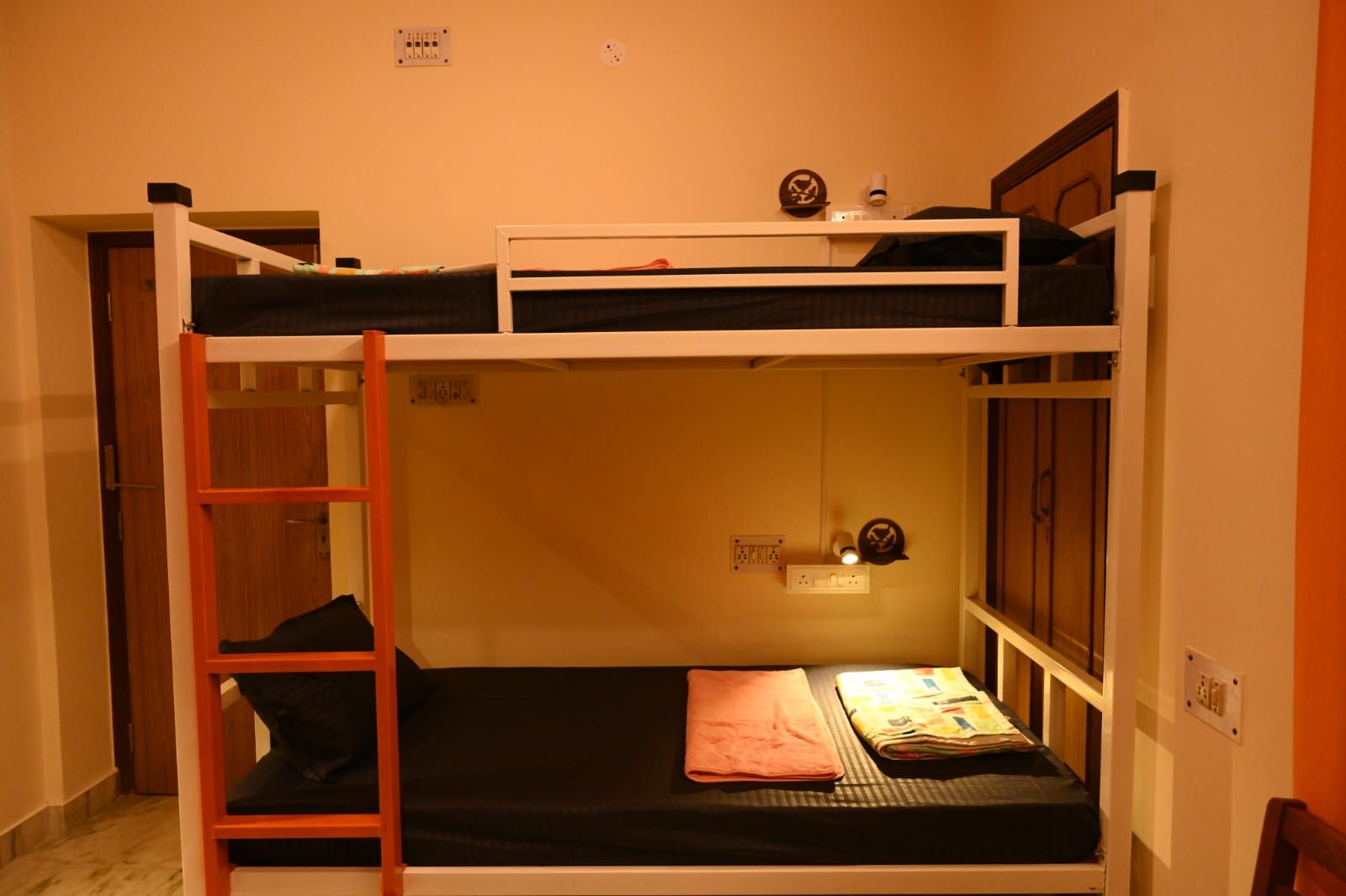Ein Etagenbett mit einer Leiter, einer kleinen Ablagefläche und einer Steckdose.