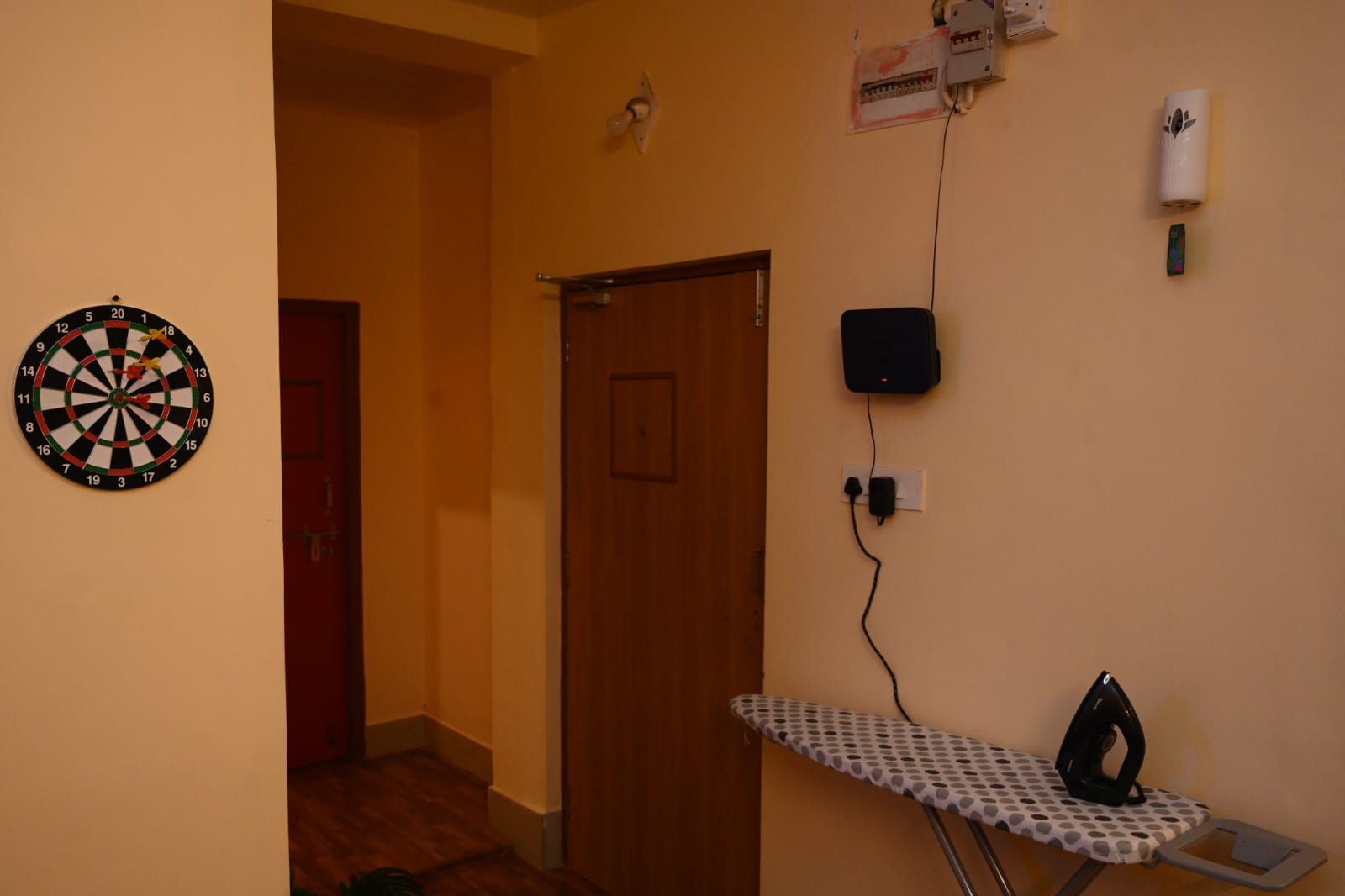 Ein Zimmer mit Dartscheibe, einer Tür, einem Bügelbrett und einer Steckdose.