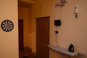 Una habitación con dardos, una puerta, una tabla de planchar y un enchufe.