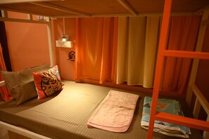 A bunk bed with a single mattress, pillows, and a blanket.