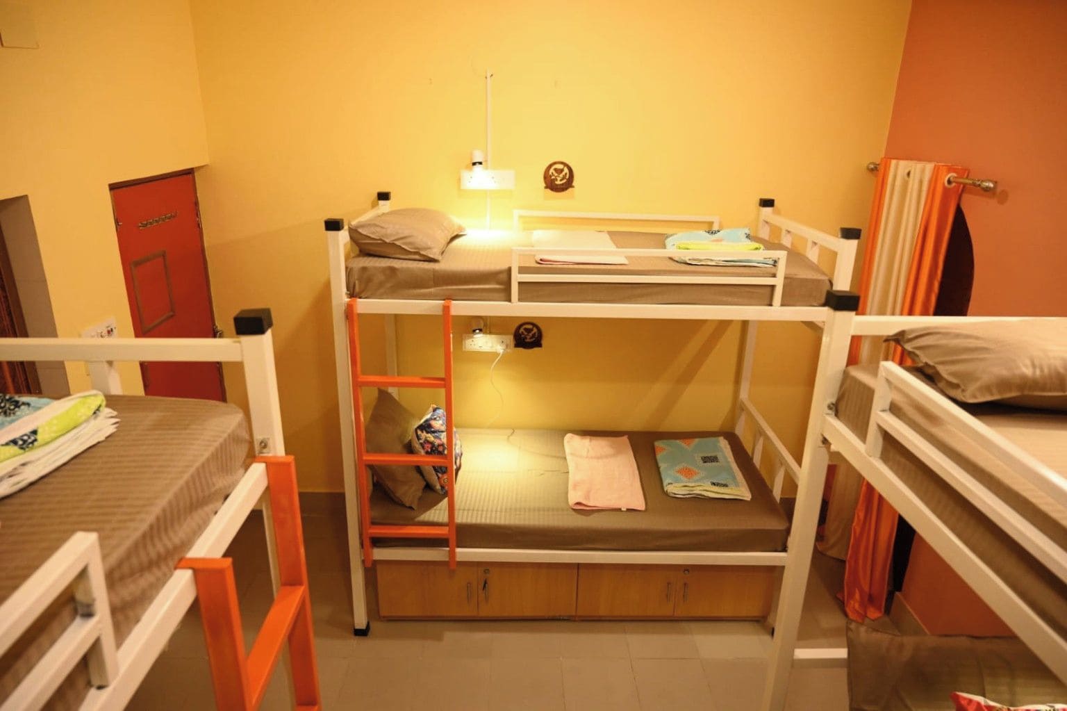 A bunk bed room with a ladder, a desk, and a red door.