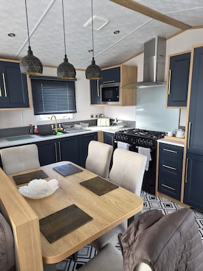A modern kitchen with a dining area, featuring a stove, microwave, and cabinets.