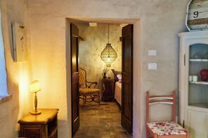 A narrow hallway with a lamp, a chair, a table, and a hanging light fixture. - Apartment in a stone mill with panoramic view (Mombaroccio)