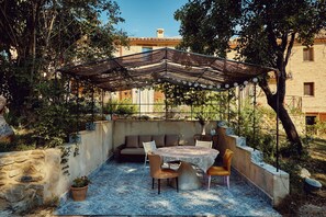 An outdoor patio with a table and chairs, a covered seating area, and a stone wall. - Apartment in a stone mill with panoramic view (Mombaroccio)