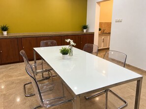 Un espace repas moderne avec une table blanche, des chaises transparentes et des plantes en pot.