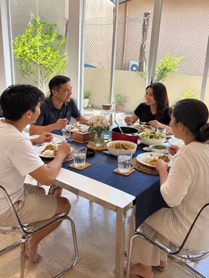 Un gruppo di persone a tavola con diversi piatti, bicchieri e un vaso di fiori.