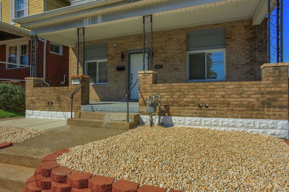 A two-story brick building with a covered porch and a gravel driveway.
