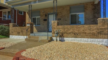 A two-story brick building with a covered porch and a gravel driveway.