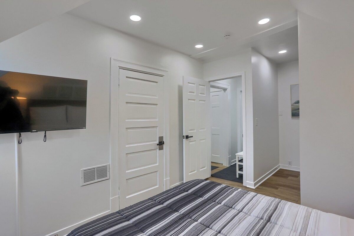 A bedroom with a bed, a television, and white doors.