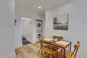 A dining area with a table and chairs, a washing machine, a fire extinguisher, and a clock on the wall. - Brookline, Pioneer 3 Stylish & Cozy 2 Bedroom Private Apartment (Pittsburgh)