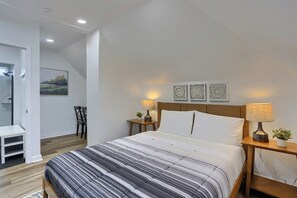 A bedroom with a bed, two bedside tables, a nightstand, a chair, a small table, and a painting on the wall. - Brookline, Pioneer 3 Stylish & Cozy 2 Bedroom Private Apartment (Pittsburgh)