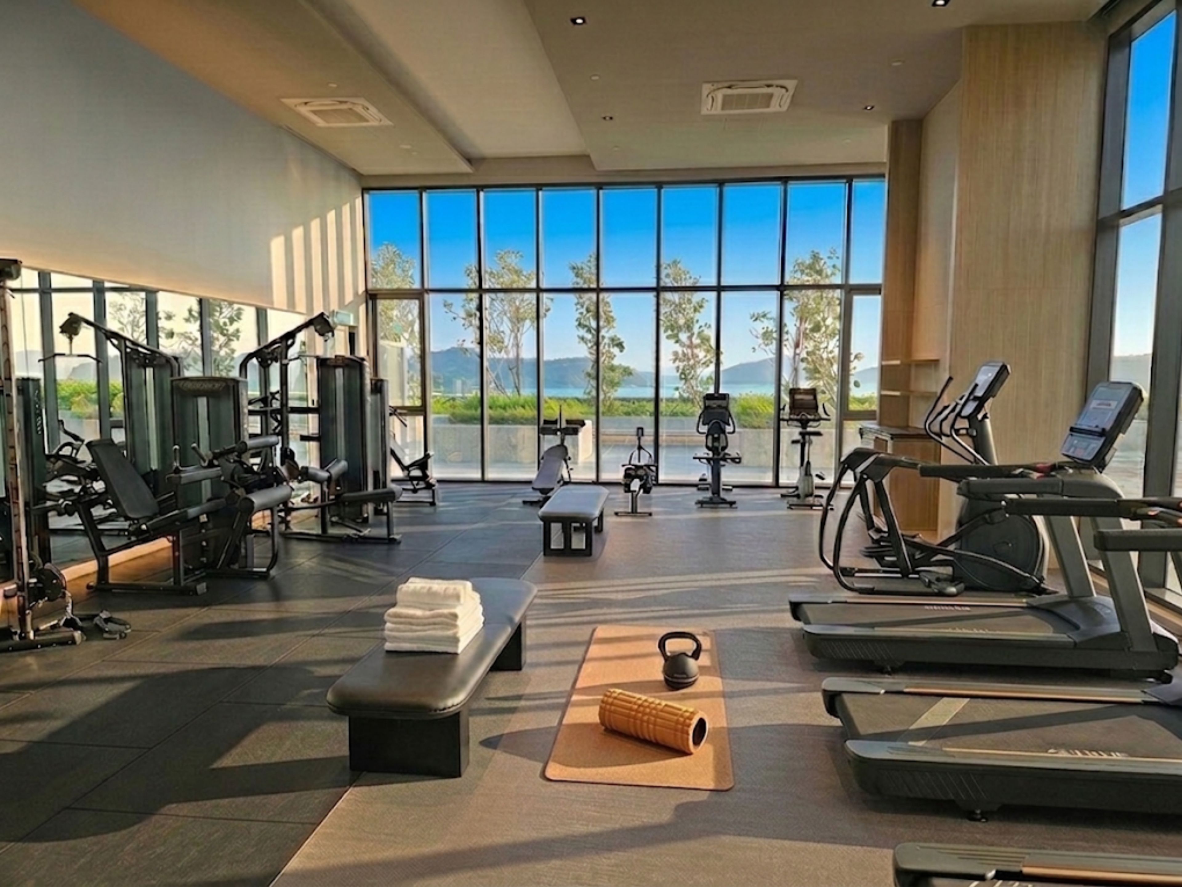 A gym with various exercise equipment, a bench, and a yoga mat.