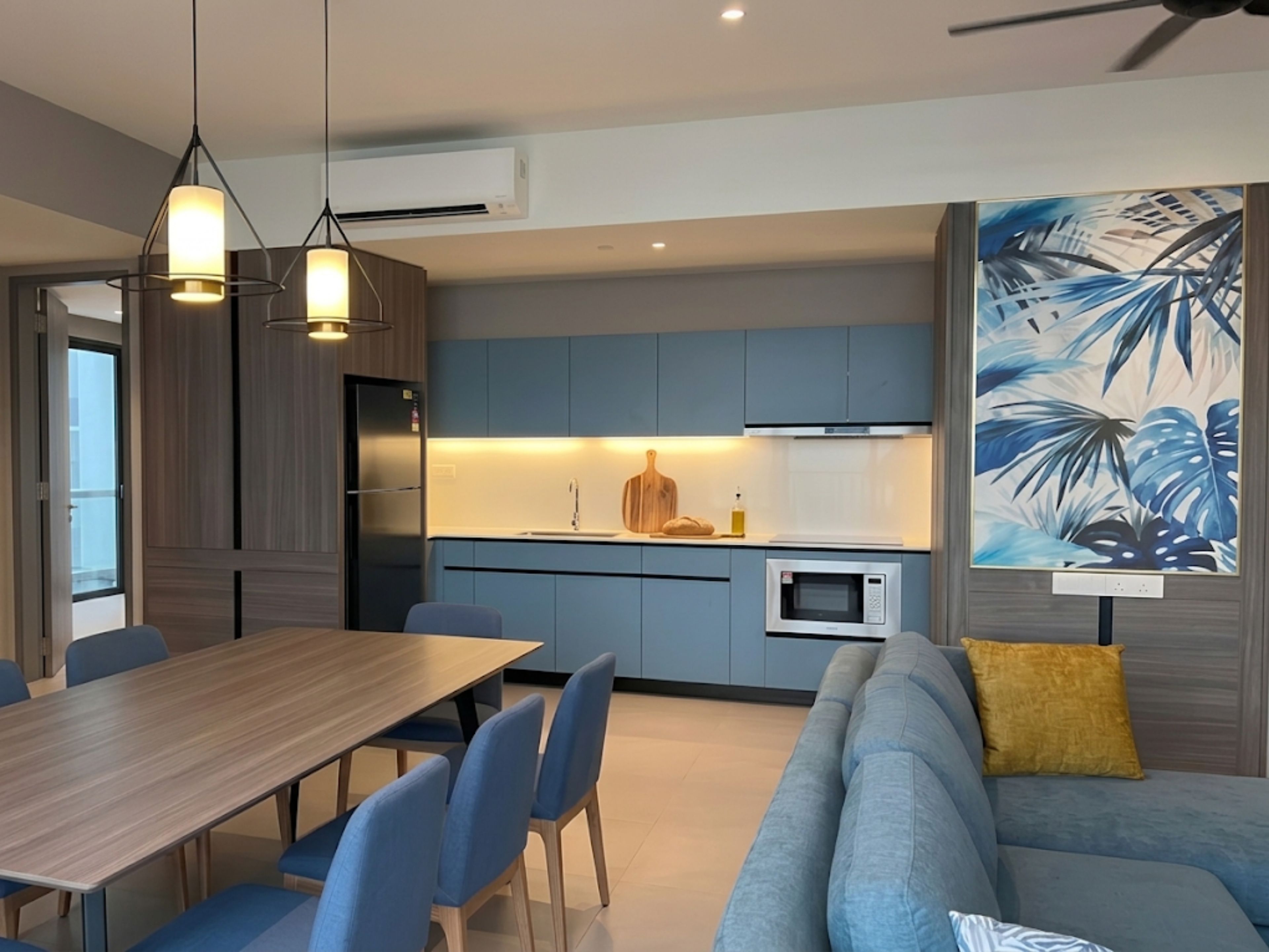 A modern kitchen with a dining area, a sofa, and a ceiling fan.