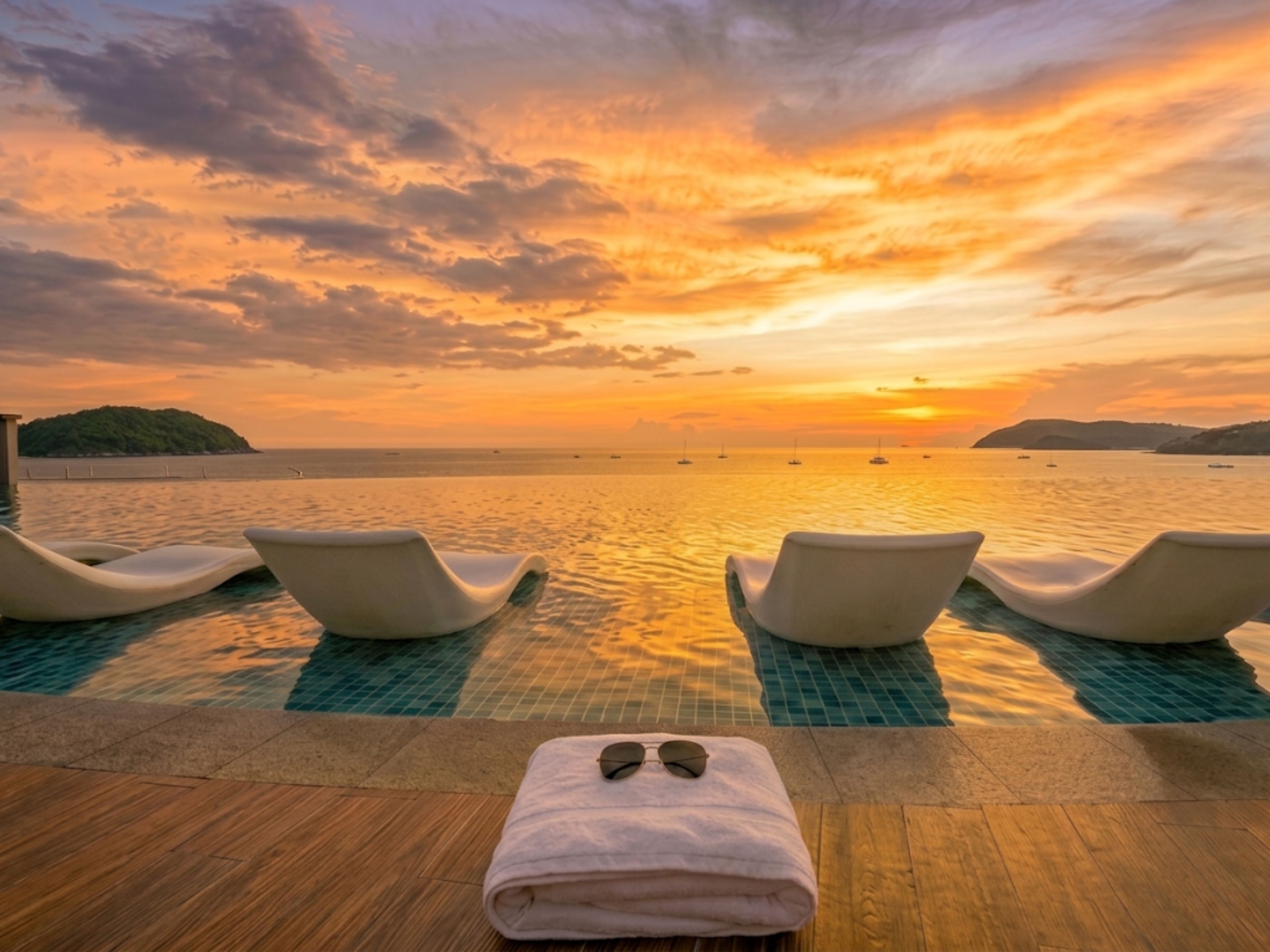 Oceanfront infinity pool with in-water loungers at golden sunset