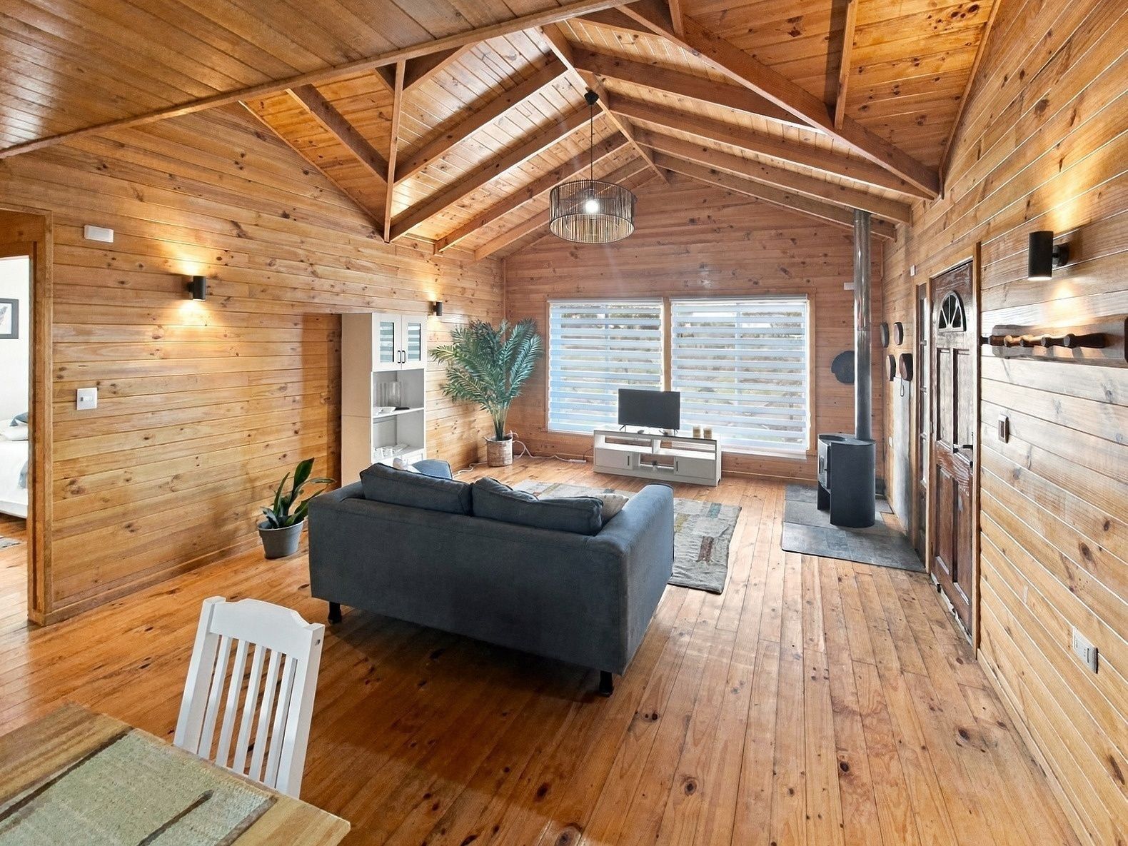 Un interior espacioso de madera con techo alto, un sofá, un televisor y una chimenea.